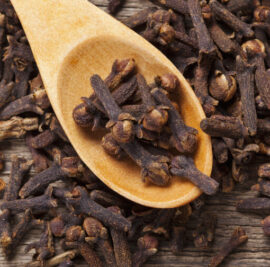 Closeup of cloves in wooden teaspoon on wooden background; Adobe RGB color space;